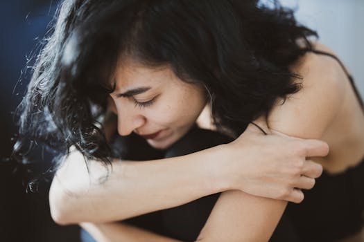 pexels-photo-3356489-3356489-4 A woman with dark hair appears pensive and emotional, sitting indoors, arms crossed.